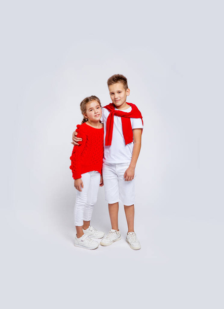 roztomilý chlapec a dívka oblečená v červené a bílé oblečení objímání - Fotografie, Obrázek