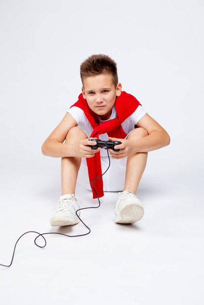 подросток эмоционально играет в компьютер или консольную игру, используя джойстик
.  - Фото, изображение