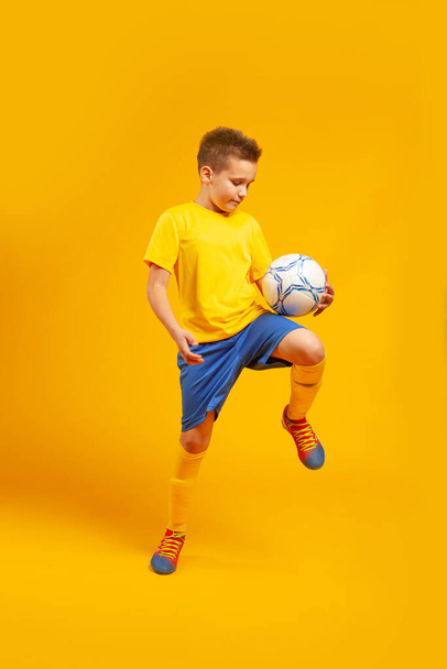 garçon joue ballon de football sur un fond jaune
 - Photo, image