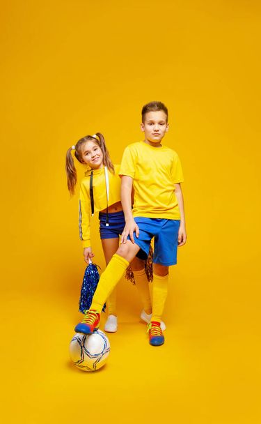 Uma rapariga da claque espreita atrás de um jogador de futebol. Ambos estão vestidos de azul e amarelo
. - Foto, Imagem