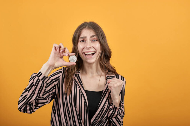 Chica feliz sonriendo y sosteniendo moneda Bitcoin
 - Foto, Imagen