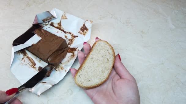 Chica de cámara lenta esparciendo mantequilla de nuez de chocolate en rodaja de ciabatta
 - Imágenes, Vídeo
