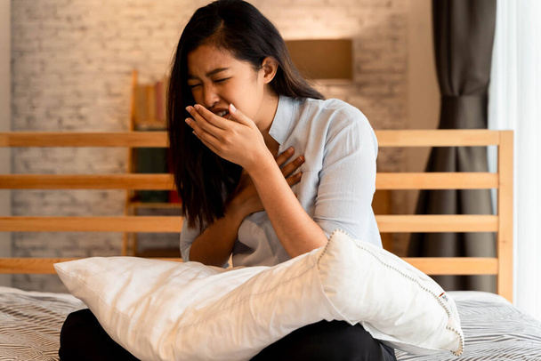 Portrait of 20s young Asian woman having dry cough in bedroom at home - Photo, Image