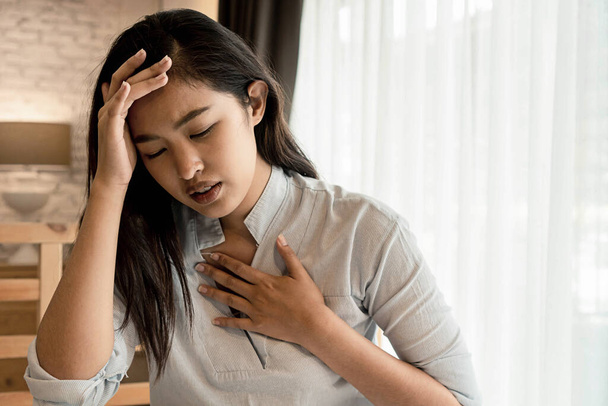 Muotokuva 20s nuori aasialainen nainen, jolla on hengitysvaikeuksia makuuhuoneessa yöllä. Hengenahdistus, astma, hengitysvaikeudet
 - Valokuva, kuva