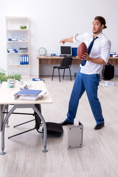 Jeune employé masculin lançant une balle de rugby dans le bureau
 - Photo, image