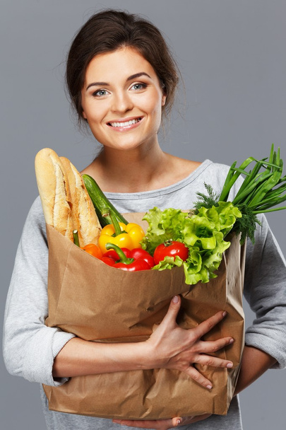 mosolygó fiatal barna nő, élelmiszerbolt zsák tele friss zöldségekkel - Fotó, kép