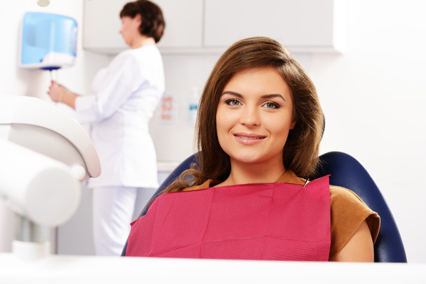 jonge brunette vrouw met mooie glimlach bezoeken tandarts - Foto, afbeelding