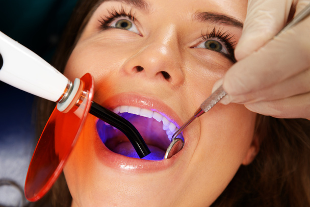 Jeune femme patient arrêtant le traitement avec l'équipement de lumière dentaire Uv - Photo, image