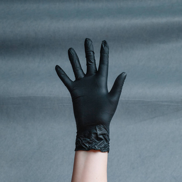 Hand in nitrile glove of gold color on a gray background with a gradient. Square aspect ratio - 写真・画像