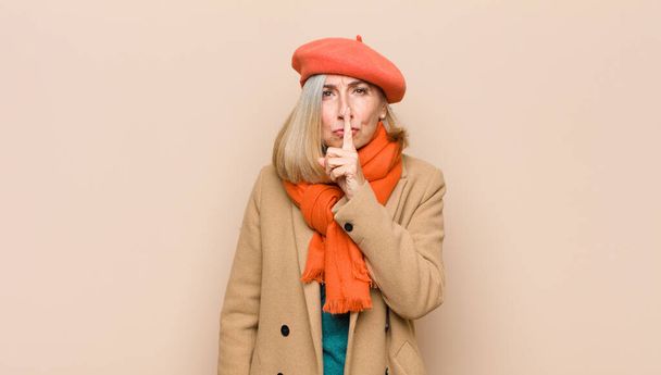 senior or middle age pretty woman asking for silence and quiet, gesturing with finger in front of mouth, saying shh or keeping a secret - Photo, Image