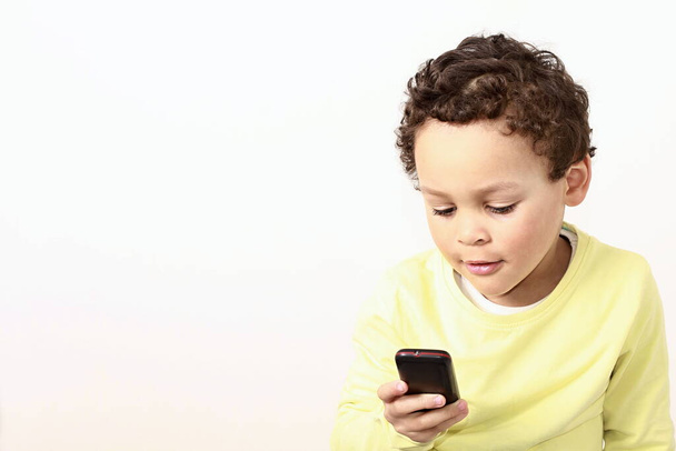 白い背景の上に隔離されたスマートフォンを持つアフリカ系アメリカ人の少年 - 写真・画像