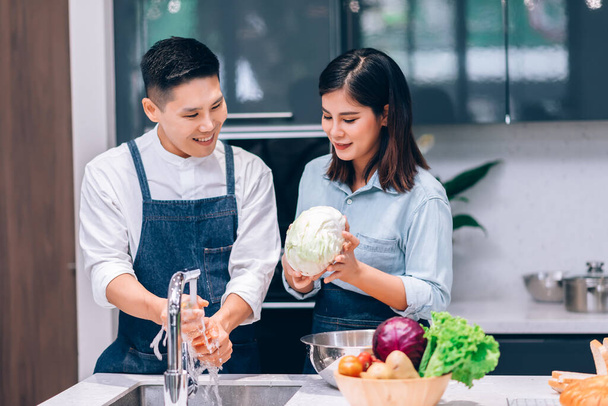 Boldog ázsiai pár főzés együtt és mosás zöldségek a konyhában otthon - Hobby Lifestyle Concept - Fotó, kép