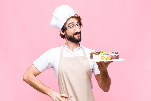 young crazy baker man confectionery concept against pink wall - 写真・画像