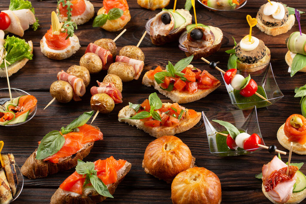 Set of different food snacks and appetizers on wooden background. Beautiful catering banquet buffet table. - Photo, image