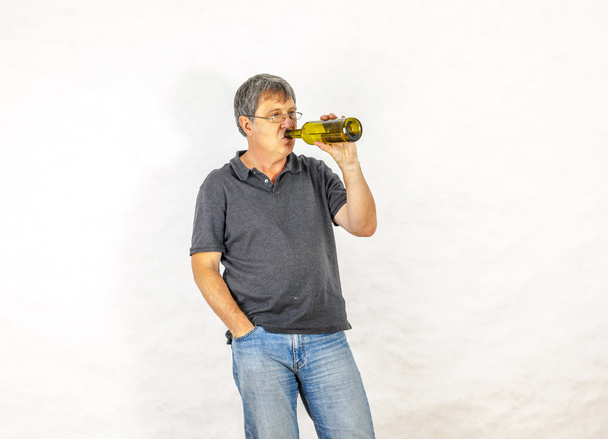 man drinks alcohol out of a bottle - 写真・画像