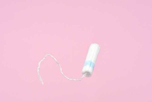 Medical female flyeng tampon on a pink background. Hygienic white tampon for women. Cotton swab. Menstruation, means of protection. Tampons on a pink background. - Photo, Image