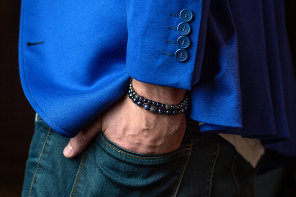 Pulseira masculina em sua mão, casaco azul, belas jóias
 - Foto, Imagem