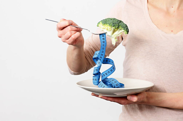 mulher segurando um garfo, brócolis e fita métrica - Foto, Imagem