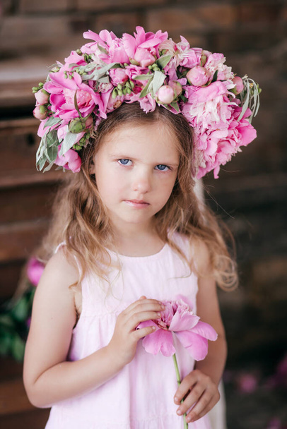 Πορτρέτο του όμορφου μικρού κοριτσιού στο στούντιο με παιώνιες - Φωτογραφία, εικόνα