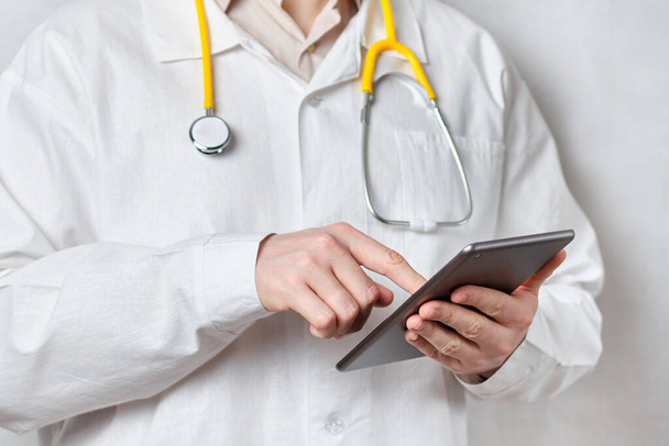 The doctor works and draws up a treatment plan on the tablet. Close up. - Foto, Imagen