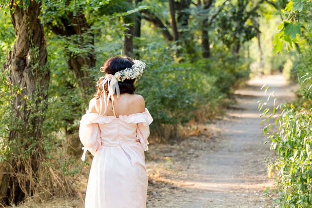Винтажное свадебное платье. Прекрасная стройная невеста в парке. фото сзади. боковой свет. Тропинка вдаль. невеста брюнетка
. - Фото, изображение