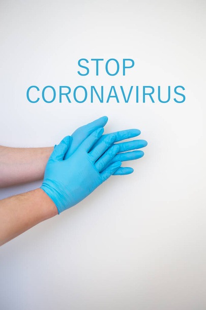 Χέρια σε μπλε ιατρικά γάντια μίας χρήσης δείχνουν ένα μοτίβο για το πλύσιμο των χεριών, ασφαλή από μικρόβια και ιούς. Η επιγραφή σταματά coronavirus. - Φωτογραφία, εικόνα