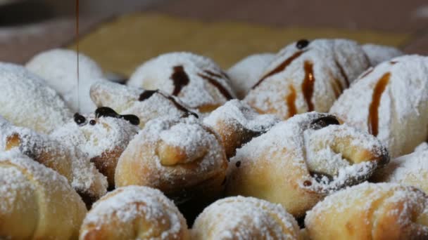 Pasteles caseros, bollos de croissant recién hechos espolvoreados con azúcar en polvo y glaseado de chocolate líquido en la cocina casera
 - Metraje, vídeo