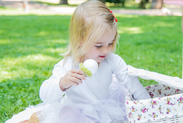 Egy gyönyörű kislány sétál a parkban piknikkosárban és szalmakalapban. Vicces érzelmes baba.. - Fotó, kép