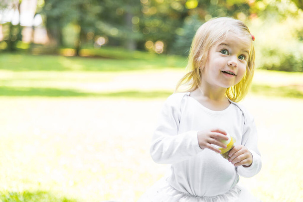 Una niña pequeña y hermosa camina por el parque con una cesta de picnic y un sombrero de paja. Bebé emocional divertido. - Foto, Imagen