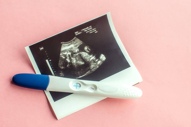 Ultrasound with positive pregnancy test on pink background. - Photo, Image