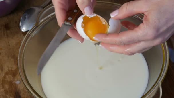 Impastare a casa facendo la pasta. Le mani femminili rompono le uova crude nel latte in uno speciale contenitore trasparente
 - Filmati, video