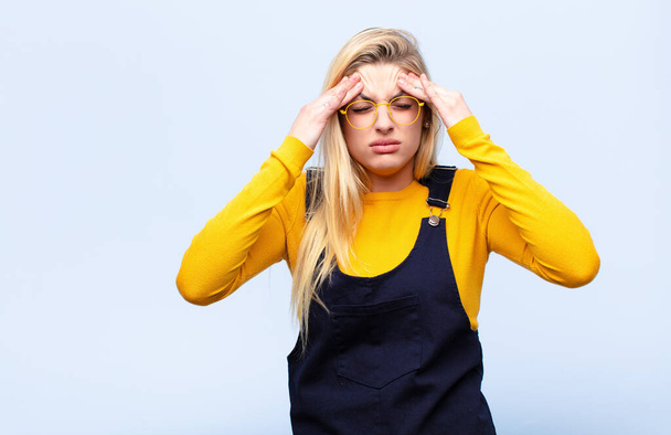 young pretty blonde woman looking stressed and frustrated, working under pressure with a headache and troubled with problems against flat wall - Foto, immagini