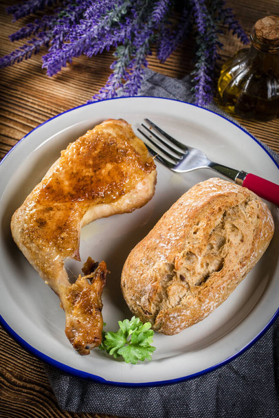 Fried chicken leg with bread roll on a plate. - Foto, afbeelding