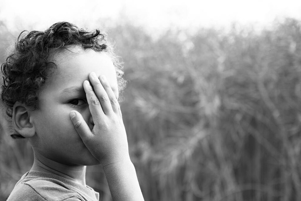 menino chorando na pobreza imagem stock com a mão sobre o rosto chorando sozinho e sozinho em fundo borrado - Foto, Imagem