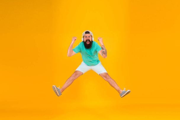 Like a rock star. happy guy wear headphones. summer vacation party. brutal hipster jump high. his favorite song. mature dj full of energy. feel freedom. celebrating success. bearded man listen music - Photo, Image