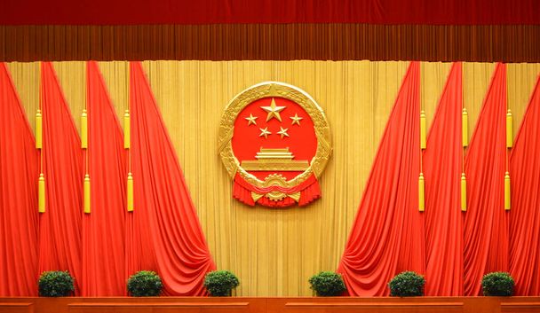 Nationaal embleem van de Volksrepubliek China en rode vlaggen in de Grote Zaal van het Volk in Peking, China - Foto, afbeelding