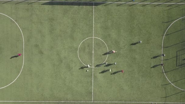 Luftaufnahme von oben nach unten von grünen Fußballsportplatz und Fußballspieler. Kleine unkenntliche Sportler auf Rasen bedeckten Stadion während der sportlichen Aktivitäten. - Filmmaterial, Video