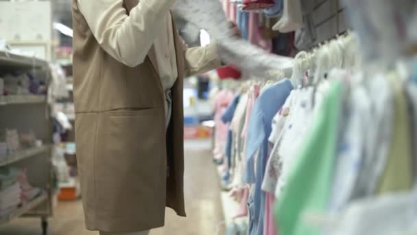 kleding pasgeboren, vrouw klant in de afdeling van kinderen kleding kiest dingen voor haar kind in het warenhuis, close-up - Video