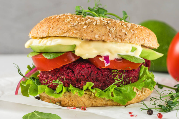 Vegan beetroot burger with avocado, salad, tomato, sprouts and vegan mayonnaise on white marble table. Healthy fast food - Fotó, kép