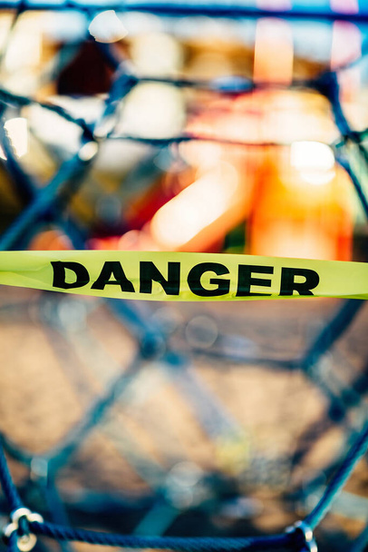 隔離の間の遊び場は、警告の徴候、 "危険"という言葉のテープで密封されます。コロナウイルスCovid-19 - 写真・画像