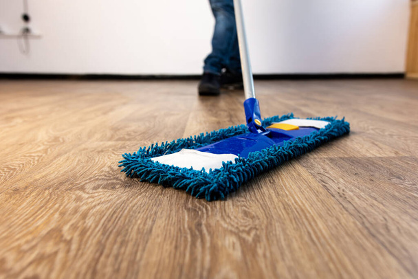 mop closeup in the hands of a man. general cleaning in the apartment and office. - Foto, imagen