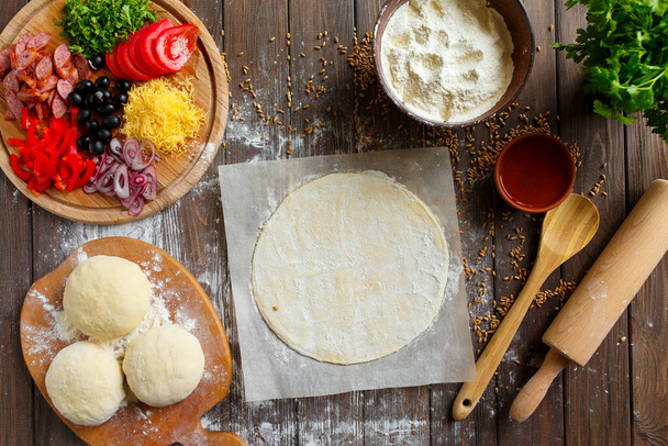 Pizza dough with ingredients on wood table - Foto, Imagem