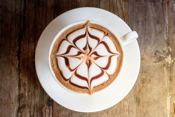 Tasse Kaffee mit schöner Latte-Art auf Holztischhintergrund - Foto, Bild
