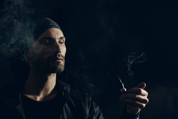 Człowiek palenie fajki na ciemnym tle - Zdjęcie, obraz