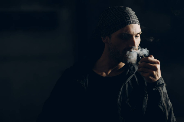 Man smoking a pipe on dark background - Photo, image