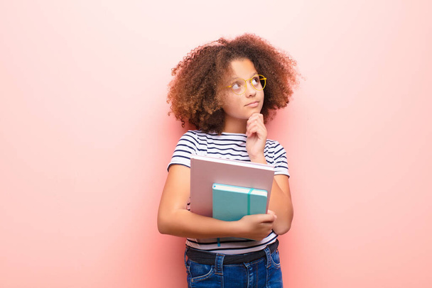 african american little girl  against flat wall holding a book - Photo, image