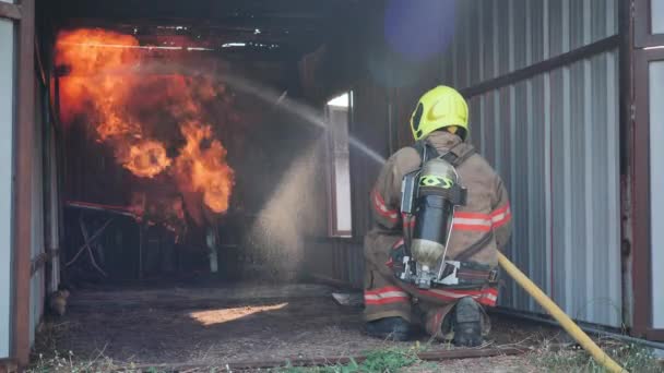 Hátul a tűzoltó tűzvédelmi ruhát visel ülni a tűzoltó edzőteremben, és sprayvíz tűz a tűzoltó állomáson Lassú mozgás. Tűzoltó karrier, Gyakorló tűzriadó koncepció. - Felvétel, videó