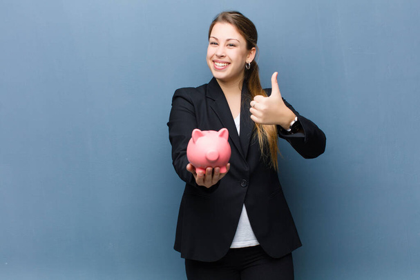 young blonde woman with a piggy bank against grunge wall background - Foto, immagini