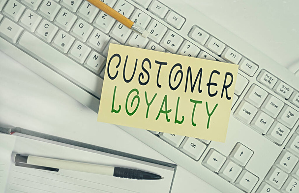 Handwriting text writing Customer Loyalty. Concept meaning result of consistently positive emotional experience White keyboard with note paper and clips on white background. - Photo, Image
