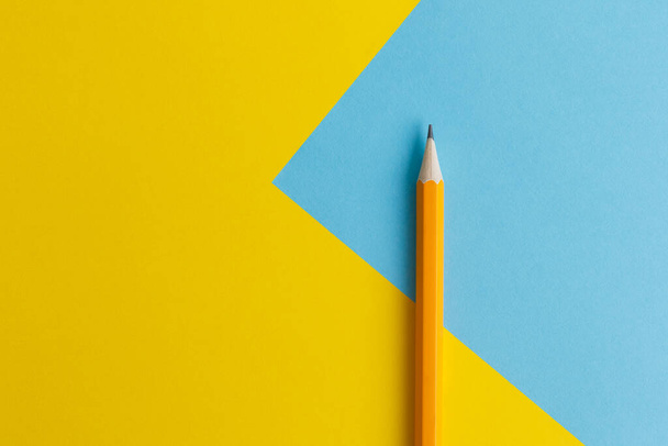 Een interactieve fotosamenstelling van een oranje potlood en ruimte voor creatief denken (tekst) wordt gebruikt voor presentatie op het gebied van onderwijs, bedrijfsleven of creativiteit. Verlichting op een potlood in de studio. Blauwe en gele achtergrond - Foto, afbeelding